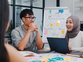 Multiracial group of young creative people in smart casual wear discussing business brainstorming meeting ideas mobile application software design project in modern office. Coworker teamwork concept.