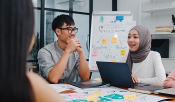 Multiracial group of young creative people in smart casual wear discussing business brainstorming meeting ideas mobile application software design project in modern office. Coworker teamwork concept.